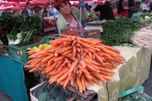 A vendor in Zagred's main square peddles carrots. A pile of carrots sold by a vendor in a market