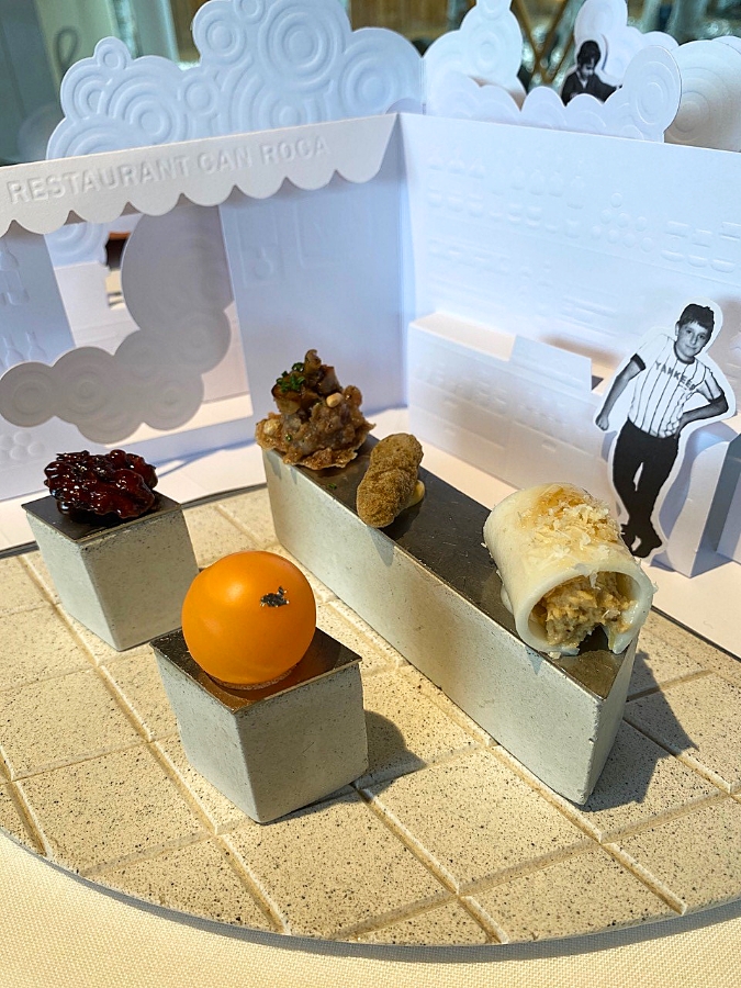 A miniature room reflecting the owners' family restaurant with nibbles of food on tables and a photo of the chef as a child.
