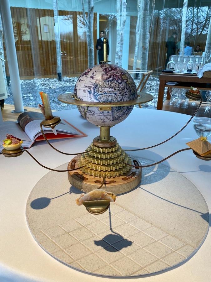 A globe on a stand with small menu items perched on outstretched perches delights at El Celler de Can Roca.