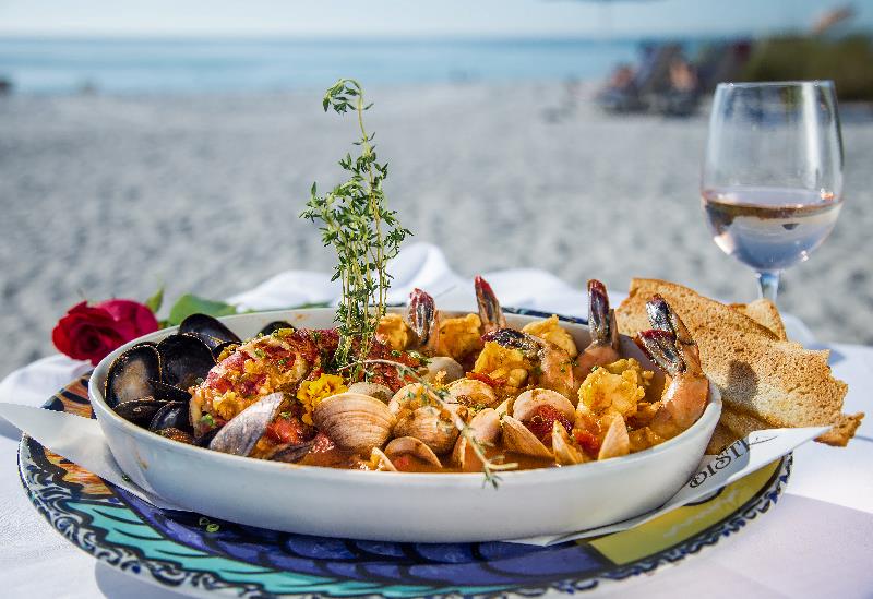 Enjoy a platter of Boullebaise with fresh herbs and a glass of wine on the beach at Beach Bistro.