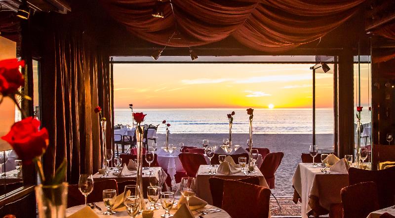 A view of the sunset on the ocean from inside Beach Bistro complete with roses on each table.