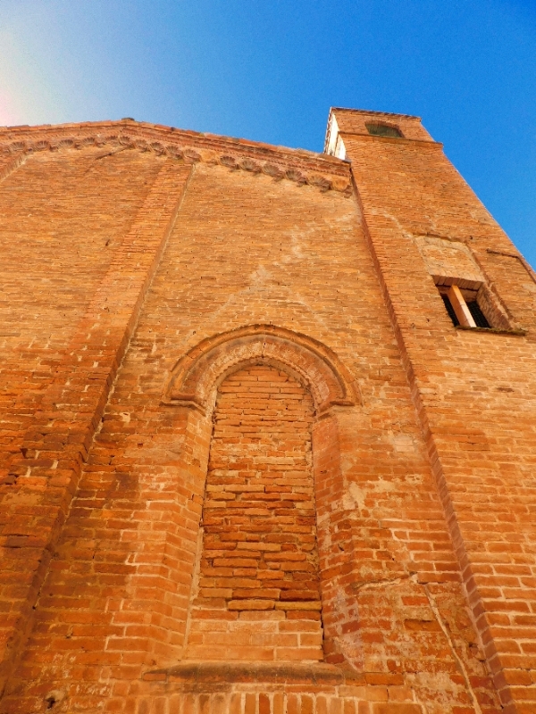 An orange brick building against a blue sky in Ferrera Italy.