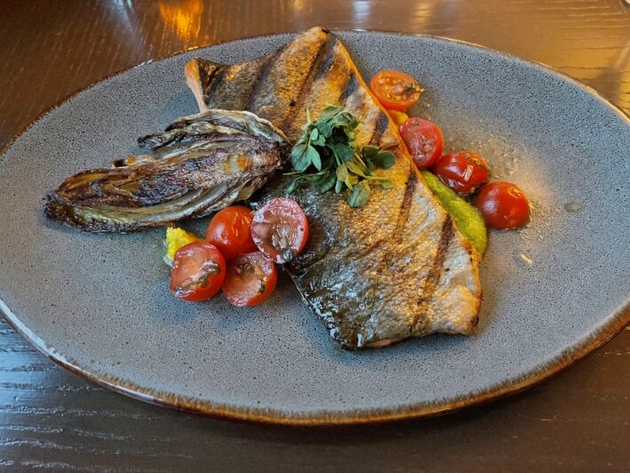 Trout on a plate with cherry tomatoes.