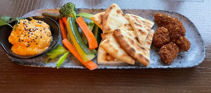 Oblong tray with sweet potato hummus, veggies, bread, and nuggets.