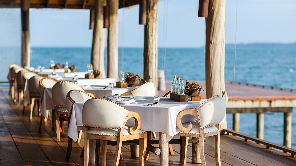 Dining tables outside on deck with ocean.