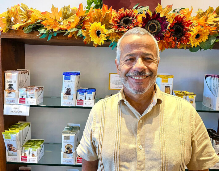 Chef Michael Antonorsi standing proudly in front of his chocolate creations at Chuao.