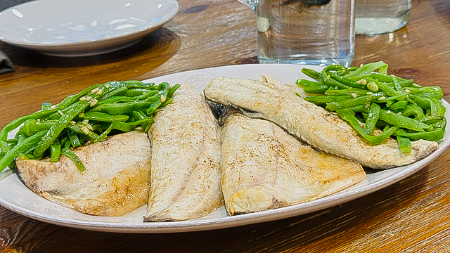 White fish with simple garlic, olive oil, black pepper served with green beans at a food lab cooking class in Portugal.