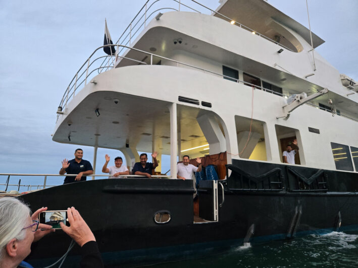 Crew waving goodbye from the Kontiki Expeditions Wayra luxury yacht.